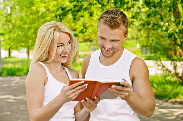 Smiling couple dressed in white reading book — Stock Photo, Image