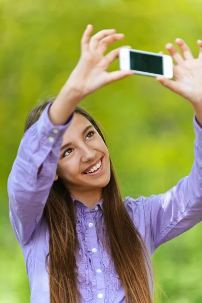 Девушка-подросток фотографирует себя со смартфоном — стоковое фото