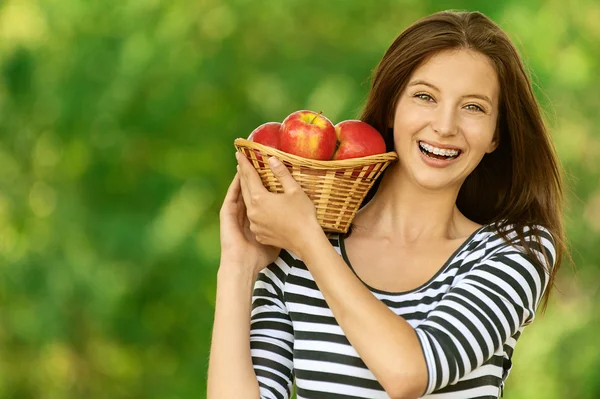 Женщина держит корзину с яблоками — стоковое фото