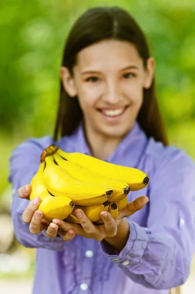 Усміхнена дівчина-підліток показує жовті банани — стокове фото