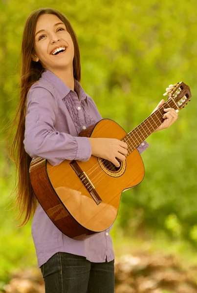 Улыбающаяся девочка-подросток играет на гитаре — стоковое фото