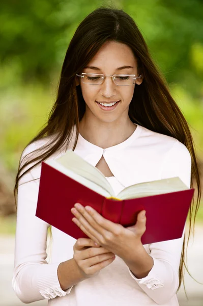 Lächelndes Teenager-Mädchen liest rotes Buch — Stockfoto