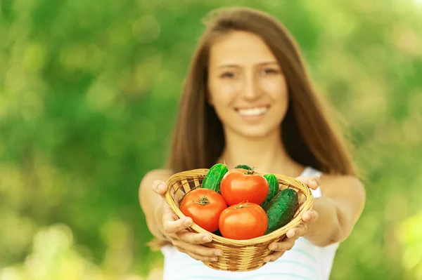 Donna che tiene cesto di pomodori e cetrioli — Foto Stock