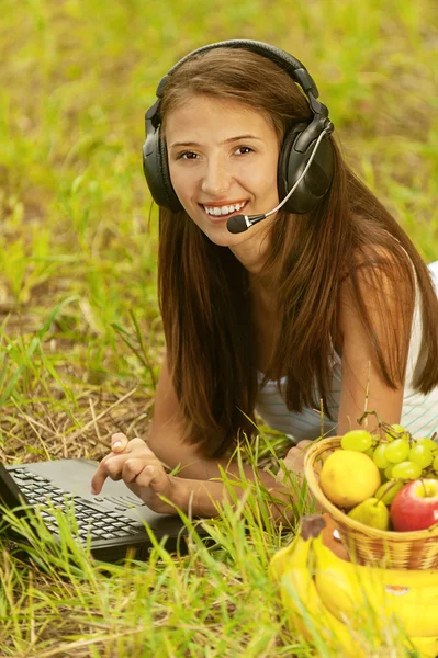 Woman with headset lie on grass — Stock Photo, Image
