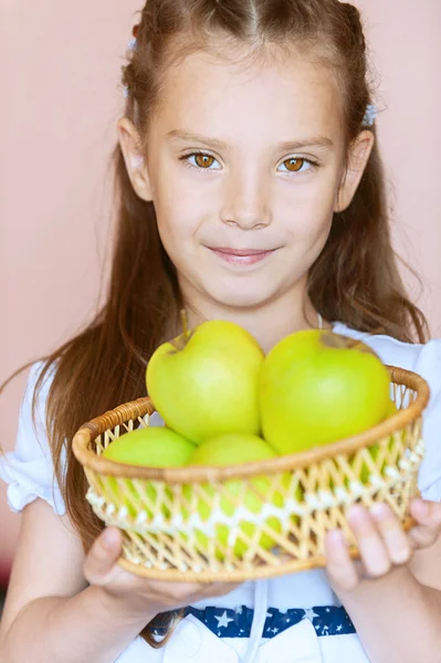 Девочка-дошкольница держит плетеную корзину яблок — стоковое фото