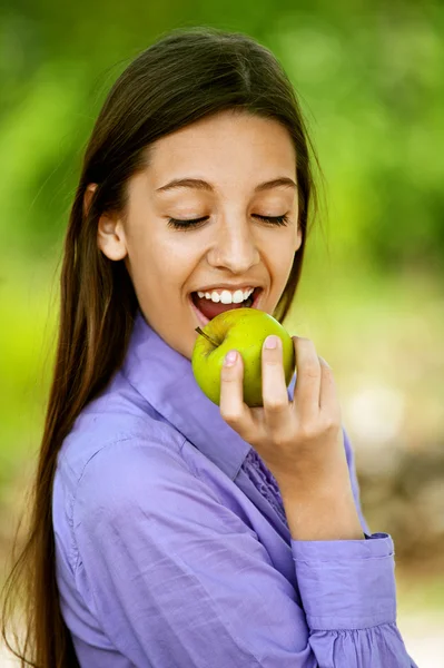 Smiling teenage girl biting an apple — Stock Photo, Image