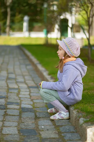 Girl-preschooler sitting on stone curb — Stock Photo, Image