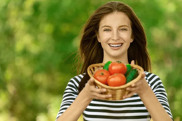 Mujer sosteniendo cesta de tomates y pepinos — Foto de Stock
