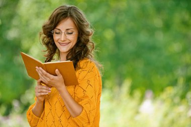 Woman in orange sweater reading book clipart