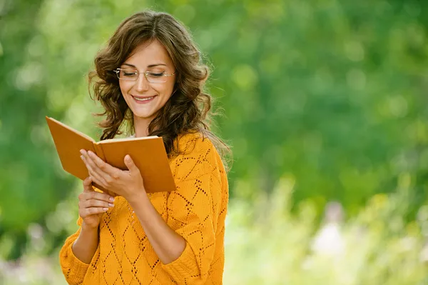 Mulher em camisola laranja livro de leitura — Fotografia de Stock
