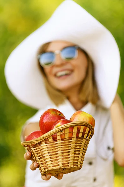 Женщина с плетеной корзиной держит красные яблоки — стоковое фото