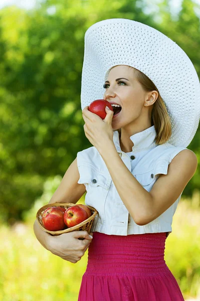 Mujer wiht cesta de mimbre sostiene manzanas rojas — Foto de Stock