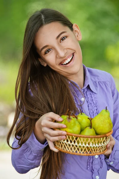 Smiling teenage girl holding basket of pears — Stock Photo, Image