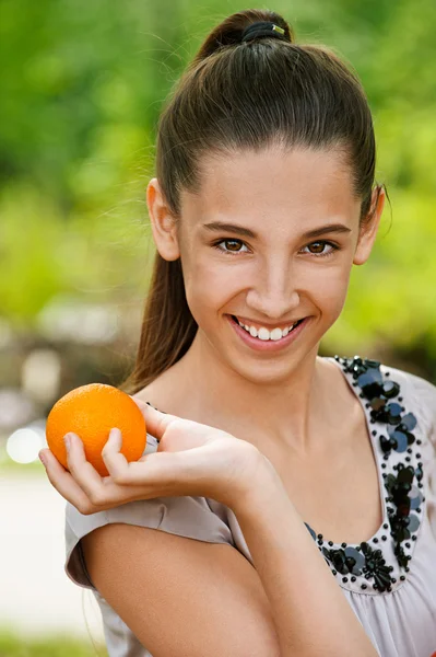 Улыбающаяся девочка-подросток с апельсином — стоковое фото