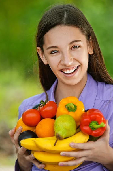 Adolescente sosteniendo plátano, pimientos, peras y naranjas — Foto de Stock