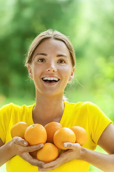 Jeune femme en chemisier jaune aux oranges — Photo