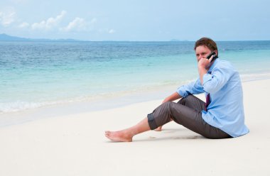 Business man calling by cell phone on the beach clipart