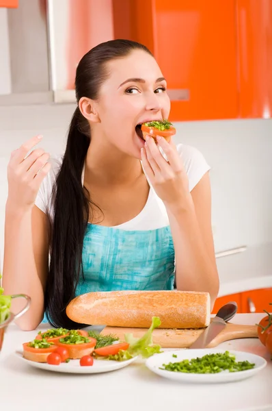 Ελκυστική γυναίκα δοκιμάζοντας φρέσκα σάντουιτς στην κουζίνα της — Φωτογραφία Αρχείου