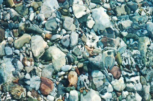 Pebbles on sea shore over water — Stock Photo, Image