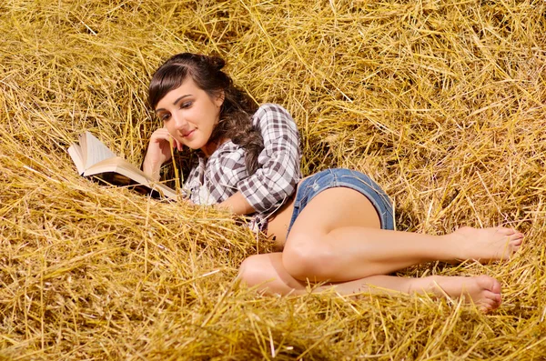 Woman reading book on haystack — Stock Photo, Image