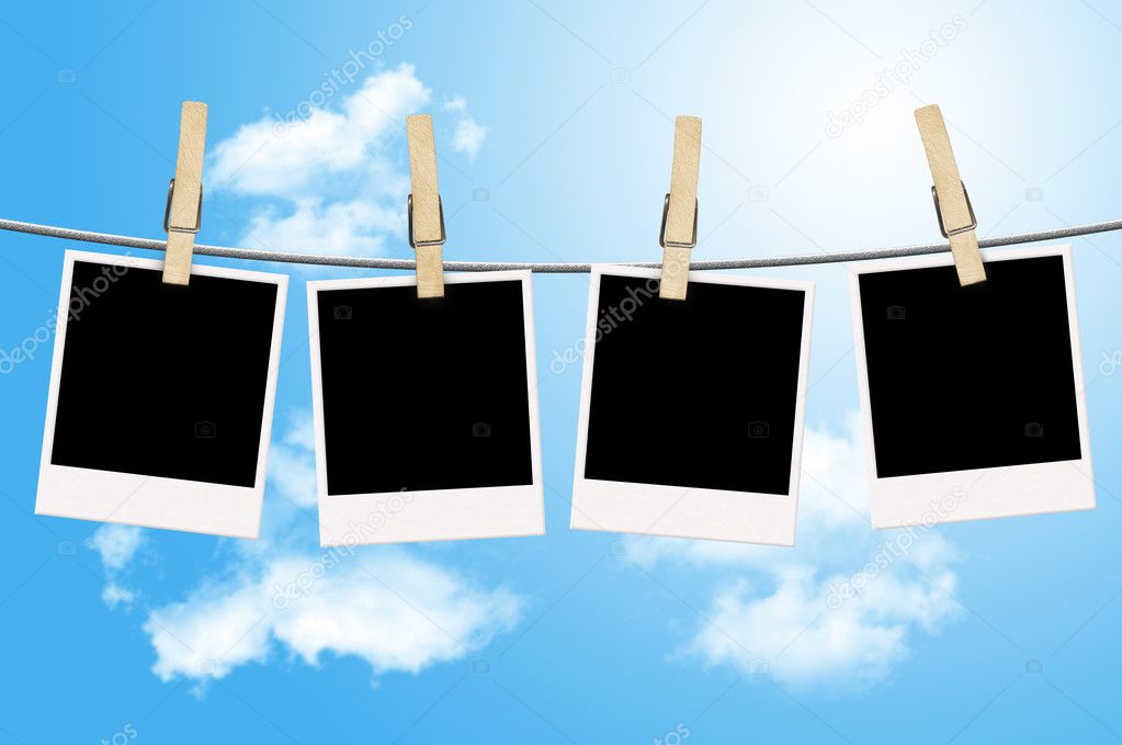 Blank photographs hanging on a clothesline with blue sky