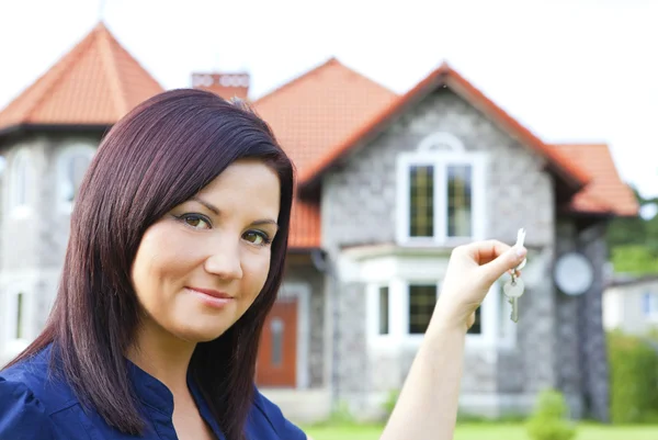 Kvinna med nycklar med hus bakgrund — Stockfoto