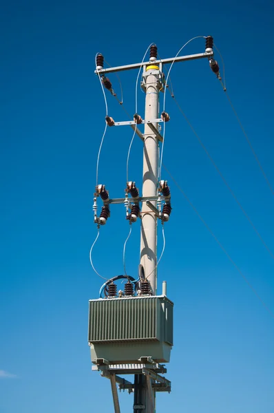 Strommast mit Isolatoren auf blauem Himmelshintergrund — Stockfoto