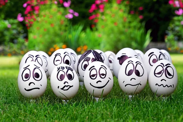 Białe jajka oraz wiele śmieszne miny, przyjęcie w ogrodzie — Zdjęcie stockowe
