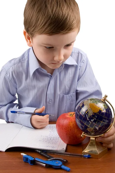 Serious boy writes in a notebook on a table — Stock Photo, Image