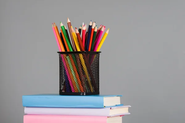 Χρωματιστά μολύβια και μια στοίβα από βιβλία — Φωτογραφία Αρχείου