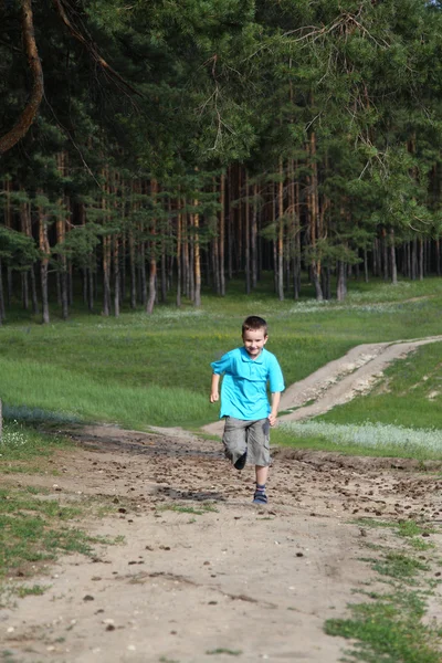 Boldog fiú fut, az erdő közelében — Stock Fotó