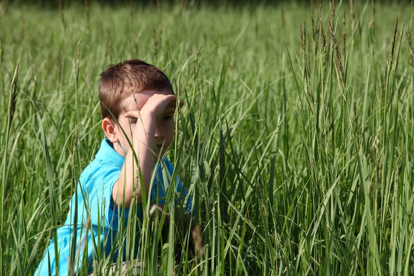 Мальчик сидит в высокой траве — стоковое фото