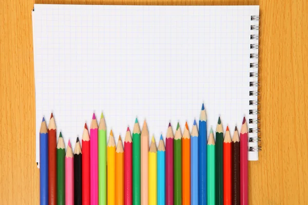 Kolorowe kredki i sprawdzone notebook — Zdjęcie stockowe