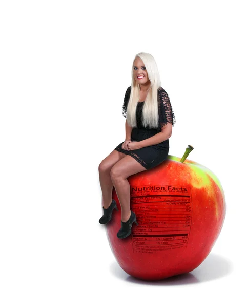 Mulher sentada no Red Delicious Apple com rótulo nutricional — Fotografia de Stock