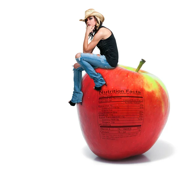 Женщина сидит на красном вкусном яблоке с этикеткой питания — стоковое фото