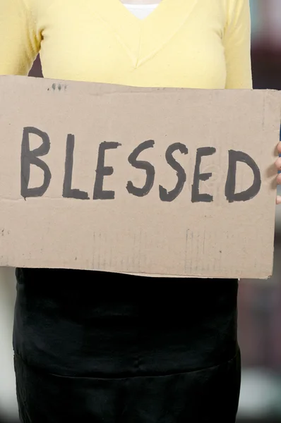 Женщина держит знак, который говорит Благословенный — стоковое фото