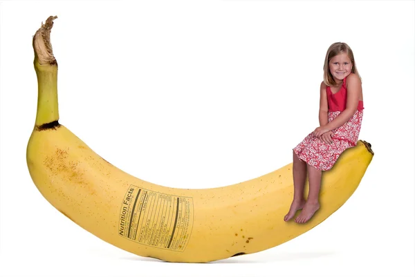 Kleines Mädchen auf Banane mit Nährwertkennzeichnung — Stockfoto