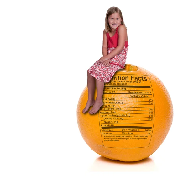 Menina sentada em laranja com rótulo nutricional — Fotografia de Stock