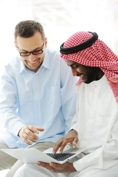 Арабские черные и кавказские мужчины работают вместе над ноутбуком — стоковое фото