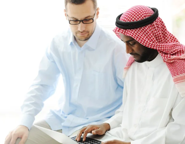 Arabski czarny i biały mężczyźni pracujący razem na laptopie — Zdjęcie stockowe