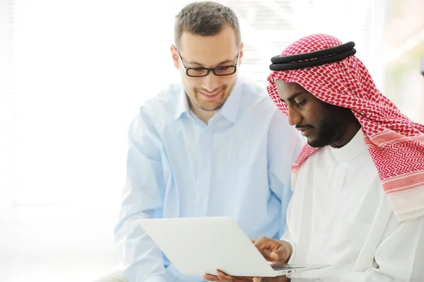 Arabski czarny i biały mężczyźni pracujący razem na laptopie — Zdjęcie stockowe