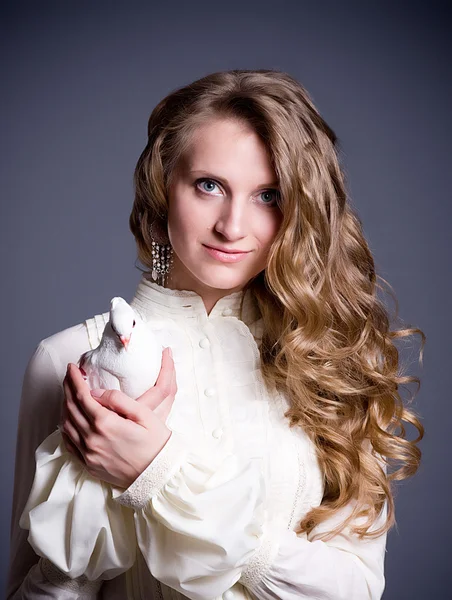 Mooie vrouw met witte duif op donkere achtergrond — Stockfoto