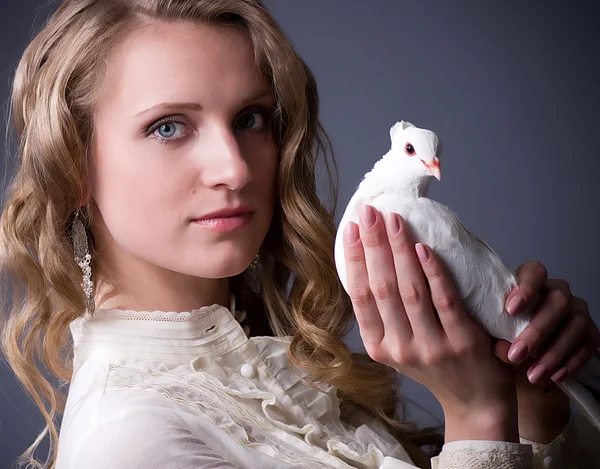 Mooie vrouw met witte duif op donkere achtergrond — Stockfoto
