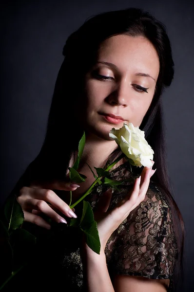 Schöne junge Frau mit weißer Rose auf dem Hintergrund — Stockfoto