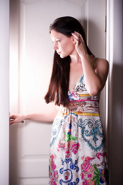 Young woman behind opened white door looking inside — Stock Photo, Image