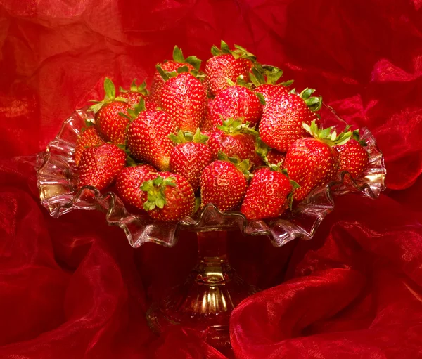 Červené čerstvé jahody v váza na červeném pozadí — Stock fotografie