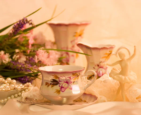 Vintage teacups, ballet dancer statuette and flowers — Stock Photo, Image