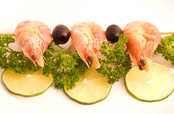 Espetos de camarão com limão e azeitonas sobre fundo branco — Fotografia de Stock