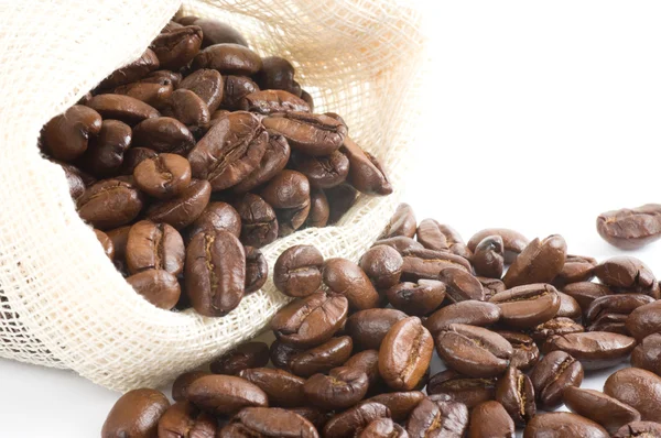 Kávová zrna v plátno pytle na bílém pozadí — Stock fotografie