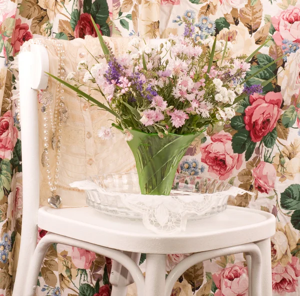 Wazon z kwiatami i kobiece tkaniny na białe krzesła — Zdjęcie stockowe